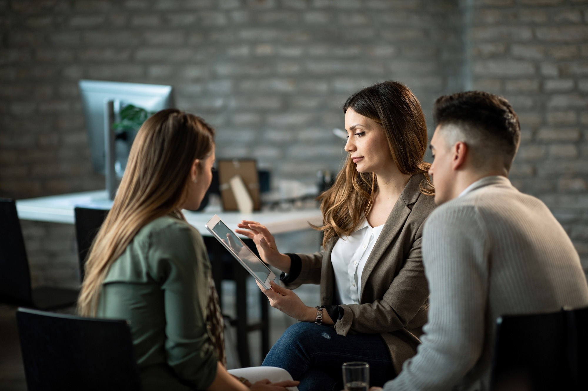 insurance-agent-using-digital-tablet-while-having-meeting-with-her-clients-office